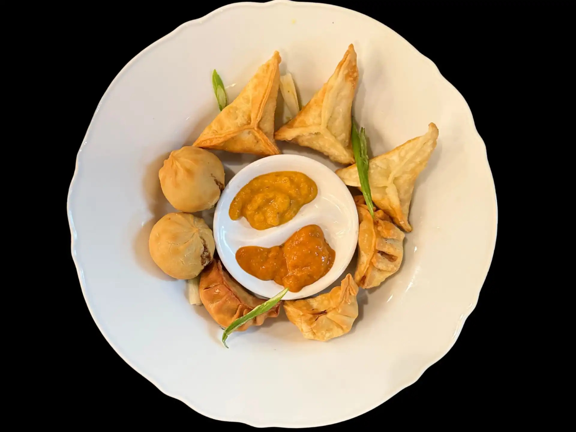 Assorted samosas and dumplings with dipping sauce